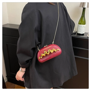 Detail der burgunderroten Abendtasche mit goldener Wellenform und Kettenriemen