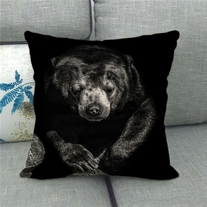 Close-up of black bear print on a square linen cushion cover on a grey sofa