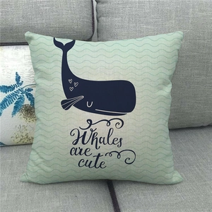 Detail of mint green linen pillowcase featuring a cute whale illustration on a grey sofa