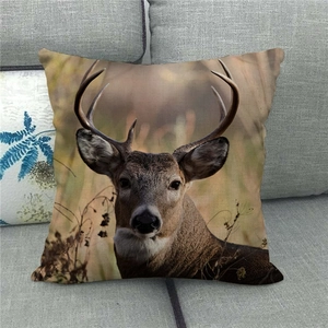 Detailaufnahme eines Leinen-Kissenbezugs mit Hirsch-Motiv auf einem grauen Sofa