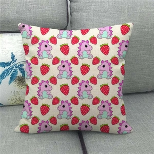 Close-up of linen cushion cover featuring purple dinosaurs and red strawberries on sofa