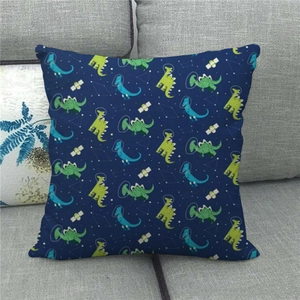 Detail of blue linen pillow cover featuring cartoon astronaut dinosaurs on a grey sofa