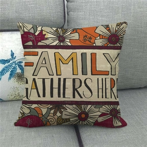 Close-up of linen pillow cover with floral wreath and 'Family Gathers Here' text