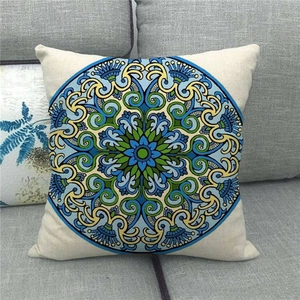 Close-up of bohemian mandala pattern on linen pillow cover against a grey sofa