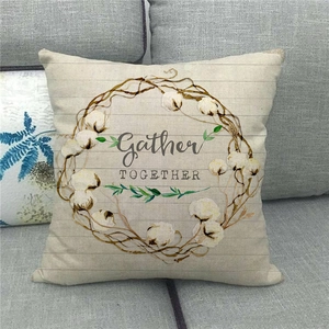 Detail of linen pillow cover with floral wreath and Gather Together text on a sofa