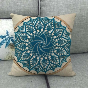 Détail du motif mandala au crochet bleu sur une housse de coussin en lin beige