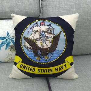 Detailed view of linen pillowcase with United States Navy emblem on a grey sofa