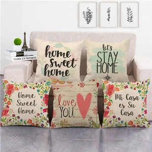 Detailed texture of five linen throw pillows with floral and heart patterns on a sofa