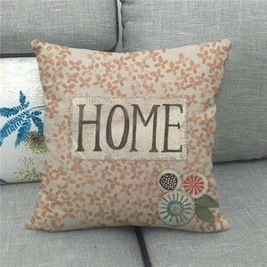 Detail of Sweet Home linen pillowcase with orange floral patterns and HOME text on sofa