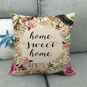 Detail of linen pillowcase with floral wreath and Home Sweet Home print on a grey sofa