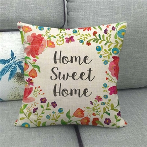 Close-up of Home Sweet Home linen pillowcase with colorful floral pattern on a grey sofa