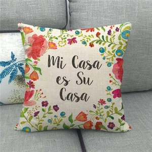 Detail of linen cushion cover with floral print and Mi Casa es Su Casa text on a grey sofa