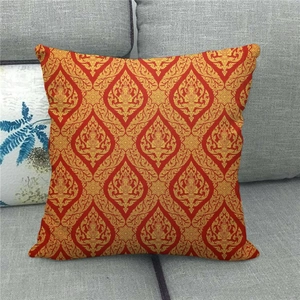 Detail von rotem Kissenbezug mit goldenem Thai-Muster auf einem grauen Sofa-Dekor