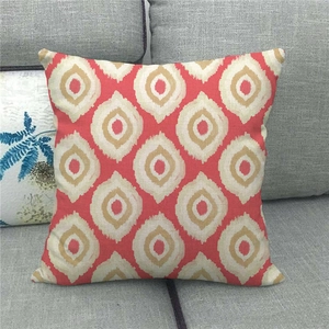 Detail der roten Leinenkissenhülle mit geometrischem Ikat-Muster auf grauem Sofa