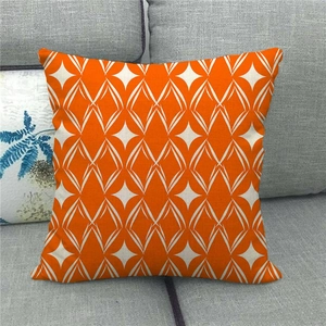 Detailaufnahme des orangefarbenen Leinenkissenbezugs mit weißem geometrischem Rautenmuster