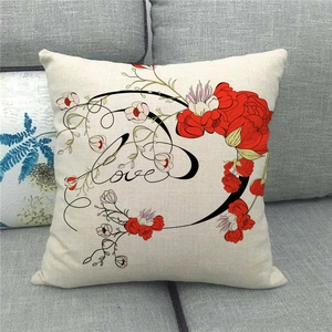 Détail de la housse de coussin en lin avec motif floral rouge et texte Love sur canapé