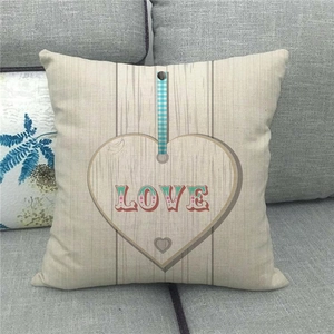Détail de la housse de coussin en lin avec motif cœur LOVE rustique sur canapé gris