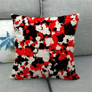 Détail de la housse de coussin carrée en lin avec motif abstrait rouge et noir sur canapé