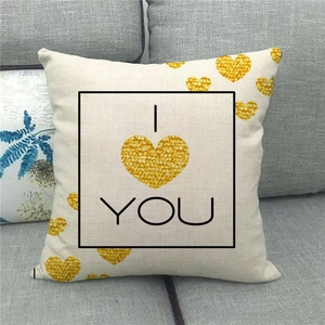 Détail de coussin en lin avec cœurs dorés et texte 'I LOVE YOU' sur un canapé gris