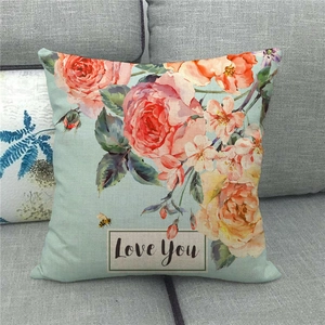 Détail de la housse de coussin en lin avec fleurs, abeille et texte Love You sur canapé