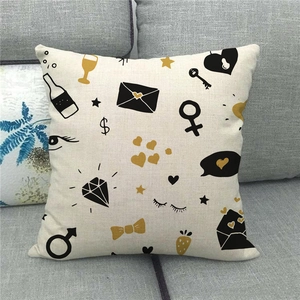 Close-up of linen pillow cover with golden heart, key, and diamond patterns on a sofa