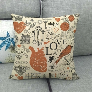Macro shot of vintage style linen pillowcase with heart and angel prints on a grey sofa