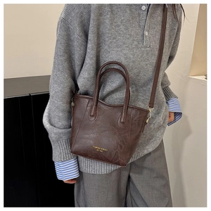 Brown lychee pattern crossbody bucket bag styled with a casual grey sweater and trousers