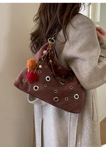 Brown suede shoulder bag with silver eyelets and colorful pompom charms worn by model