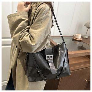 Detail of black soft leather tote bag with silver buckle strap shown on a model