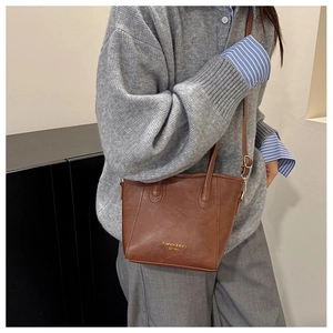 Detailed view of the brown leather bucket bag with gold lettering and adjustable strap