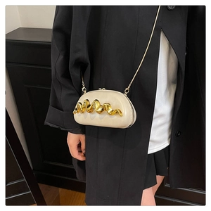 Detail des goldenen Wellenmusters auf der beigen Tasche mit eleganter Goldkette