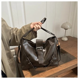 Detail of dark brown leather tote bag featuring a silver metal buckle and soft matte texture