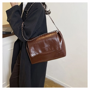Close-up of vintage brown crinkled patent leather shoulder bag with a chain strap