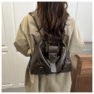 Deep brown oversized leather tote bag with silver buckle worn over a beige trench coat