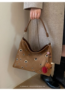 Detail of brown suede tote with metal eyelets and bohemian charms on a shoulder bag