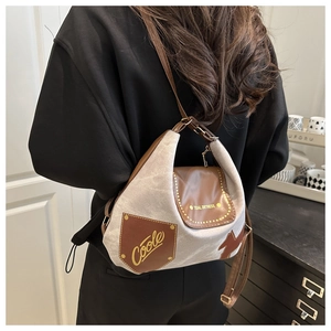 Detailed view of gray canvas and brown leather crossbody bag shown on a model