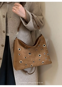 Detail of brown suede tote bag featuring metallic eyelets and minimalist shoulder strap