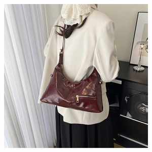 Detail der burgunderroten Lackleder-Hobo-Tasche mit Hochglanz-Finish und Metallreißverschluss
