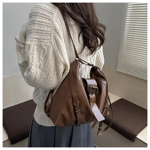 Detail of vintage brown leather tote bag worn by model in a minimalist room setting