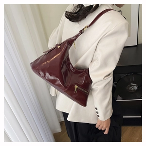 Détail du sac hobo brillant bordeaux avec ferrures dorées et poche zippée