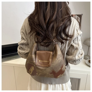 Close-up of vintage brown tote bag with dog-shaped leather patch and golden stud details