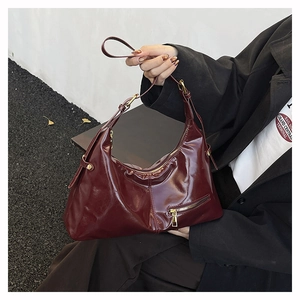 Détail du sac en cuir verni bordeaux avec fermeture éclair en métal doré élégante
