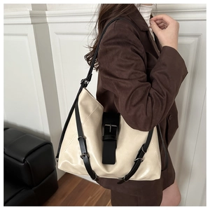 Detail of cream leather tote bag with black strap accents and metallic buckle detail