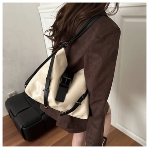Detail of a large beige soft leather tote bag with black buckle accents shown on model