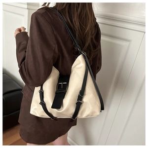 Model wearing a large cream and black contrast hobo shoulder bag in a modern studio setting