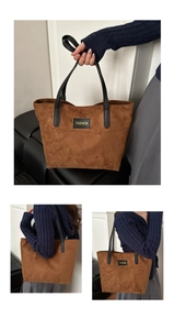 Makro-Detail der braunen Shopper-Tasche aus Wildleder mit schwarzem Fashion-Label und Lederriemen