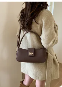 Detail view of brown suede texture shoulder bag with decorative gold metal hardware