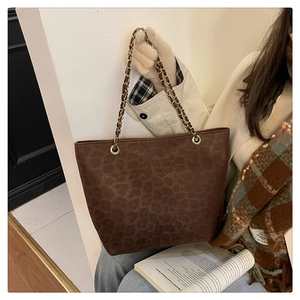 Detail of leopard print tote bag with gold chain strap in a warm lifestyle setting
