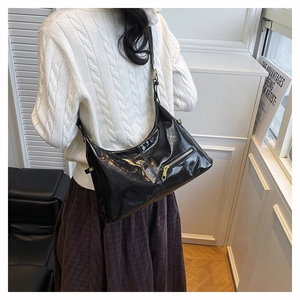 Detail of a black glossy hobo shoulder bag with gold zippers and a minimalist chic style