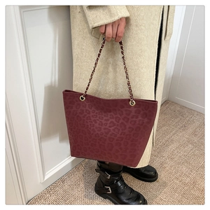 Detail of burgundy leopard print tote bag featuring gold chain strap and suede texture